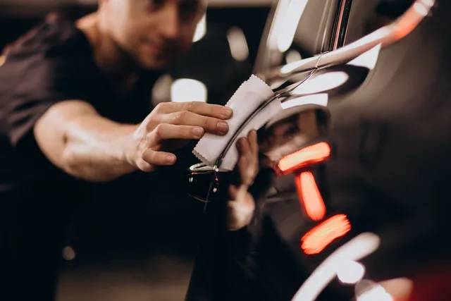 Person cleaning shiny chrome car detail with a white cloth.