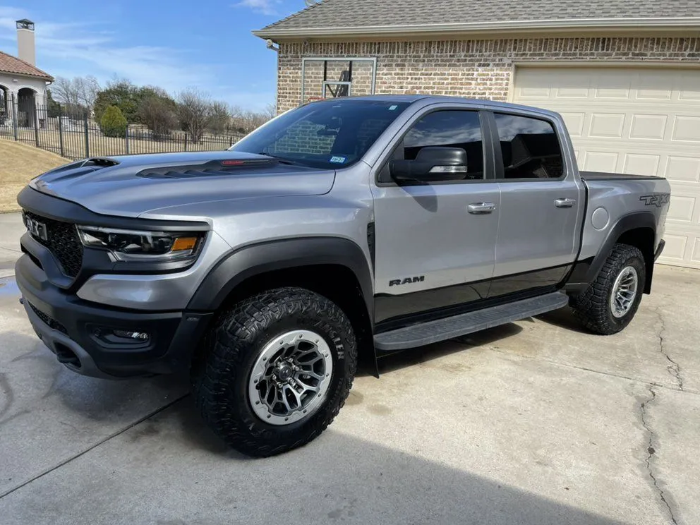 Gray Ram TRX truck parked outside a house with a concrete driveway, sunny day.