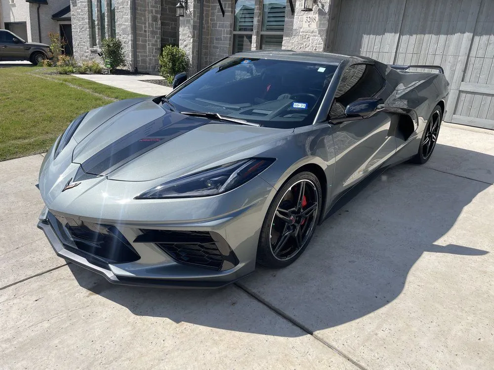 Gray Chevrolet Corvette with black racing stripes parked on a driveway.